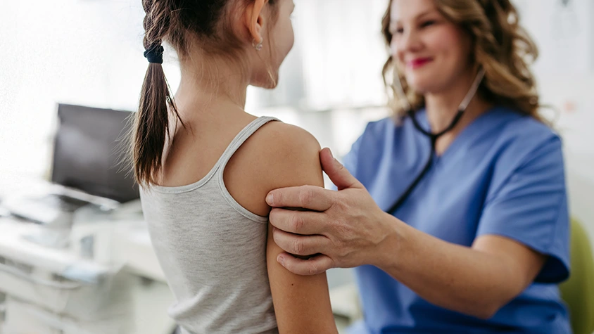 Doctor examining young girl with scoliosis